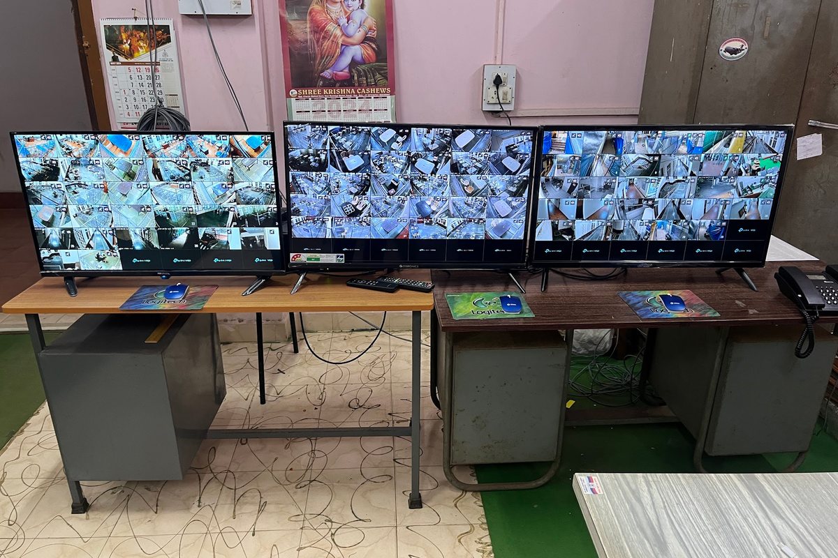 The deployed control room for the Goa election surveillance system: three monitors showing the multi-camera grid feeds across the strongrooms and counting halls